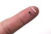 Pacemaker next to a single grain of rice on a fingertip