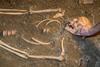 Human remains in sand being excavated by archaeologist