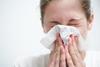 Woman blowing nose and sneezing into tissue