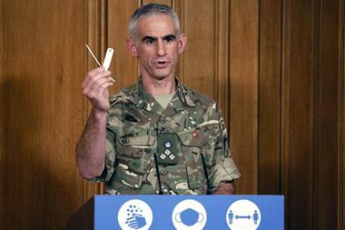 A photo of an army brigadier holding up a covid test at a press conference